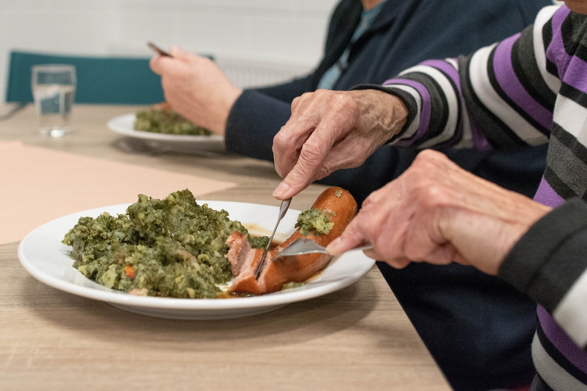 image of a plate of food and hands cutting food with knife and fork this image is decorative and represents meal services